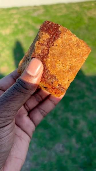 Hand holding a golden square of coffee cake outdoors
